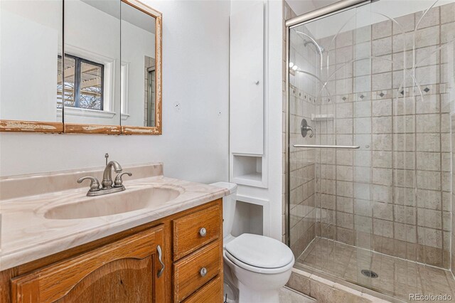 bathroom featuring vanity, an enclosed shower, and toilet