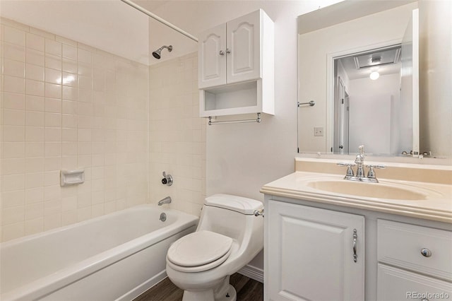 full bathroom featuring vanity, tiled shower / bath combo, toilet, and hardwood / wood-style floors