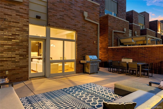 patio terrace at dusk featuring a grill