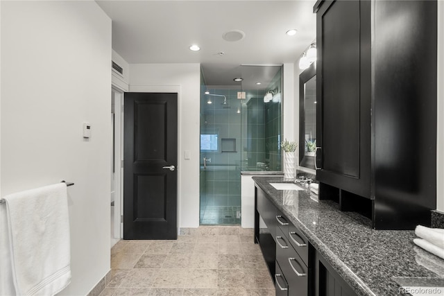 bathroom featuring a shower with shower door and vanity