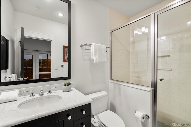 bathroom featuring toilet, an enclosed shower, and vanity