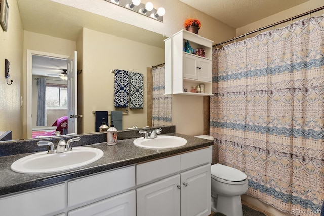 bathroom with ceiling fan, vanity, a textured ceiling, and toilet