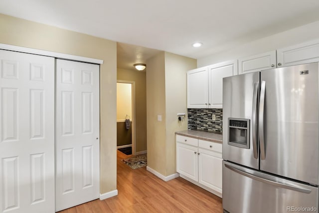 kitchen featuring light hardwood / wood-style floors, stainless steel fridge, white cabinetry, and tasteful backsplash