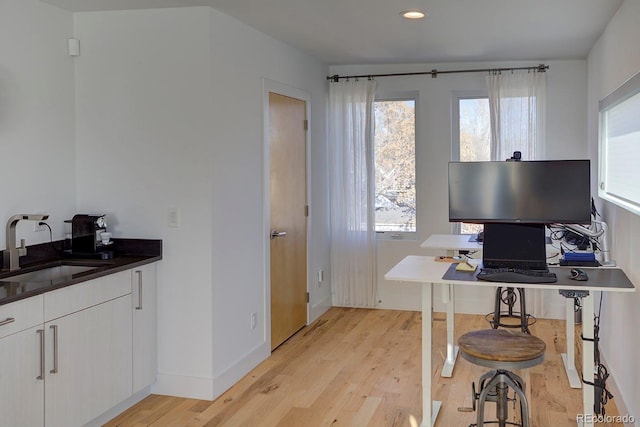 office with light wood-type flooring and sink