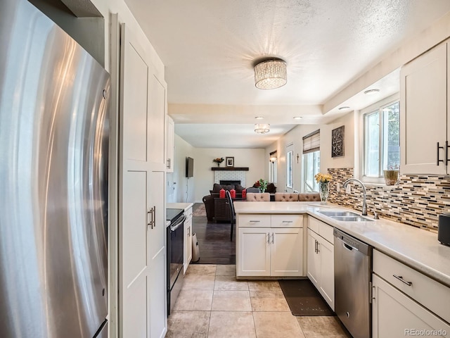 7520 Braun Ct, Arvada, CO 80005 - kitchen featuring appliances with stainless steel finishes, open floor plan, a brick fireplace, a peninsula, and light countertops