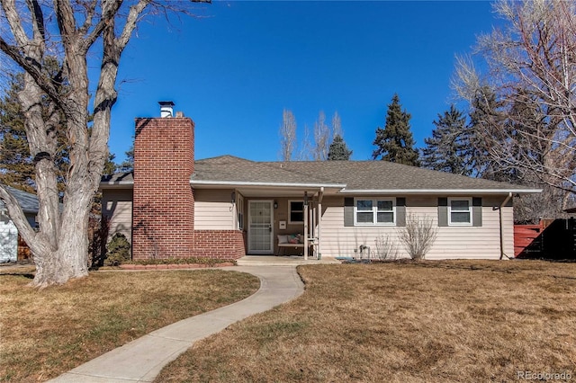 single story home with brick siding, a chimney, and a front lawn