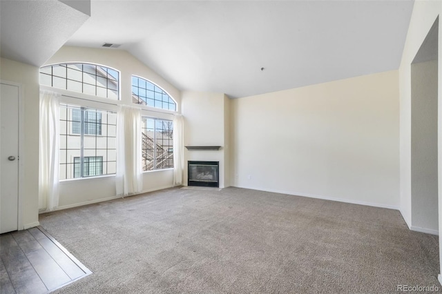2172 Denton Grv Unit 203, Colorado Springs, CO 80919 - unfurnished living room featuring carpet flooring, a fireplace with flush hearth, visible vents, baseboards, and vaulted ceiling