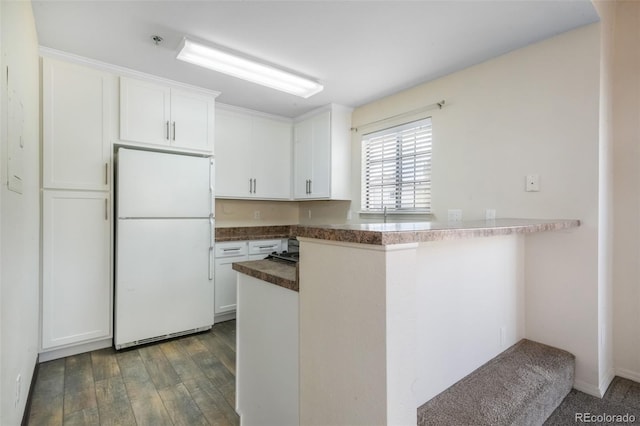 2172 Denton Grv Unit 203, Colorado Springs, CO 80919 - kitchen with freestanding refrigerator, a peninsula, wood finished floors, dark countertops, and white cabinets
