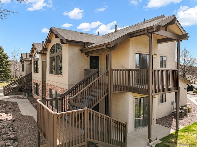 2172 Denton Grv Unit 203, Colorado Springs, CO 80919 - back of property with stairway, a shingled roof, and stucco siding