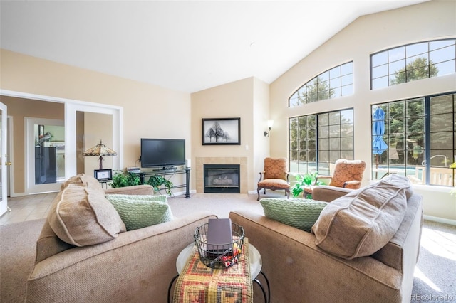 2172 Denton Grv Unit 203, Colorado Springs, CO 80919 - living area with a tiled fireplace, vaulted ceiling, baseboards, and a healthy amount of sunlight