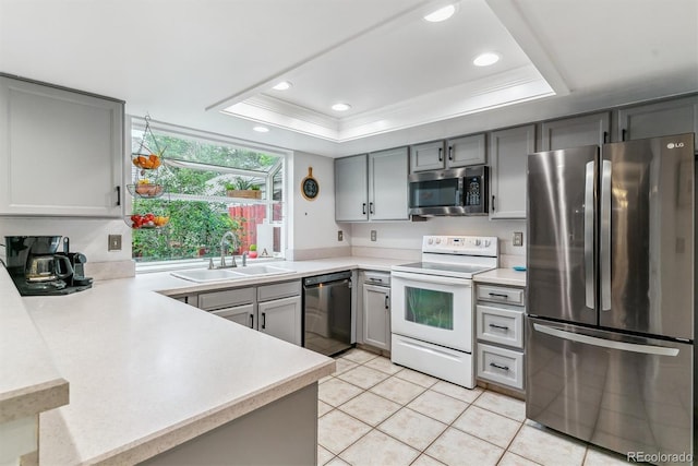 4231 S Fairplay Cir # E, Aurora, CO 80014 - kitchen with appliances with stainless steel finishes, a sink, a tray ceiling, gray cabinetry, and recessed lighting