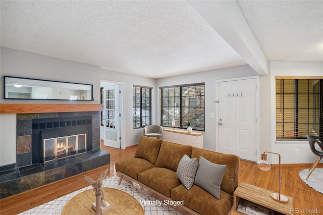 living room with a tile fireplace, wood-type flooring, and a textured ceiling