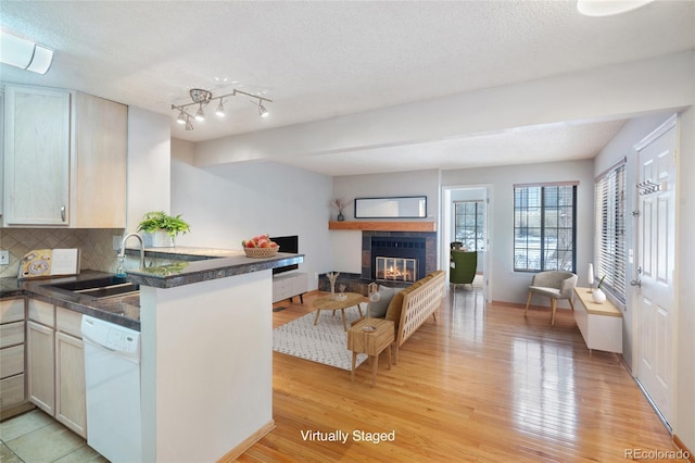 kitchen featuring sink, white dishwasher, tasteful backsplash, light hardwood / wood-style floors, and kitchen peninsula