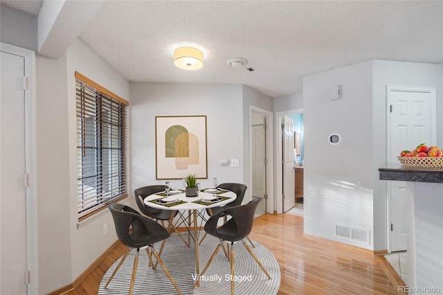 dining room featuring light hardwood / wood-style floors and a textured ceiling