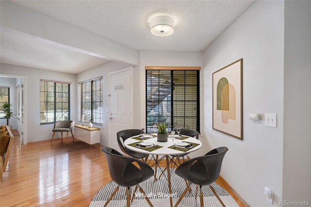 dining space featuring light hardwood / wood-style floors and a textured ceiling