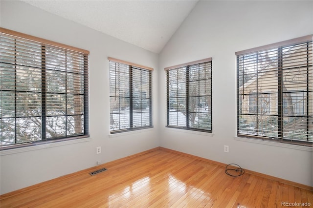 spare room featuring hardwood / wood-style flooring and vaulted ceiling