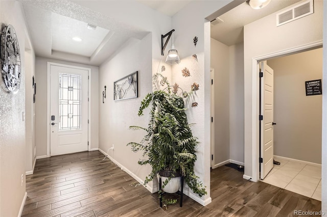 entryway featuring hardwood / wood-style floors, a raised ceiling, and a textured ceiling