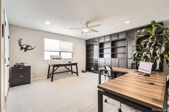 office space with light carpet, ceiling fan, and a textured ceiling