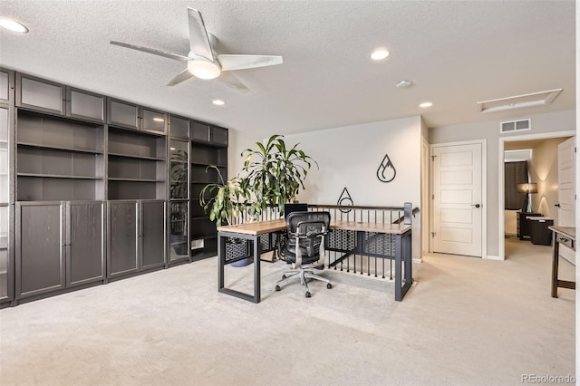 office space with light carpet, ceiling fan, and a textured ceiling