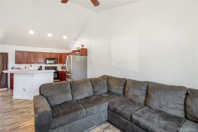 living room with high vaulted ceiling, sink, light wood-type flooring, and ceiling fan