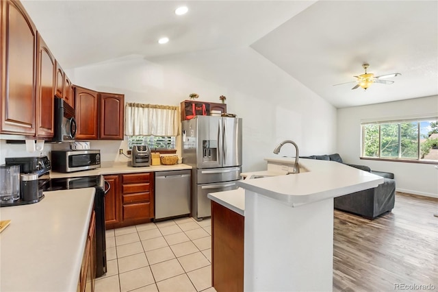 kitchen featuring lofted ceiling, light wood-type flooring, ceiling fan, appliances with stainless steel finishes, and sink