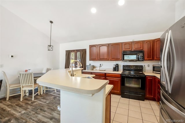 kitchen with light hardwood / wood-style flooring, black appliances, sink, pendant lighting, and lofted ceiling