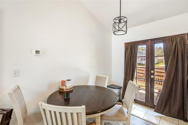 dining space with french doors, light tile patterned floors, and vaulted ceiling