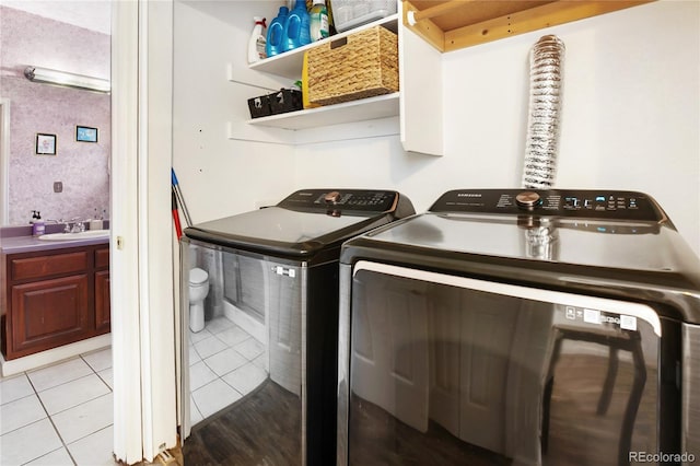 clothes washing area with washing machine and clothes dryer, sink, and light tile patterned floors