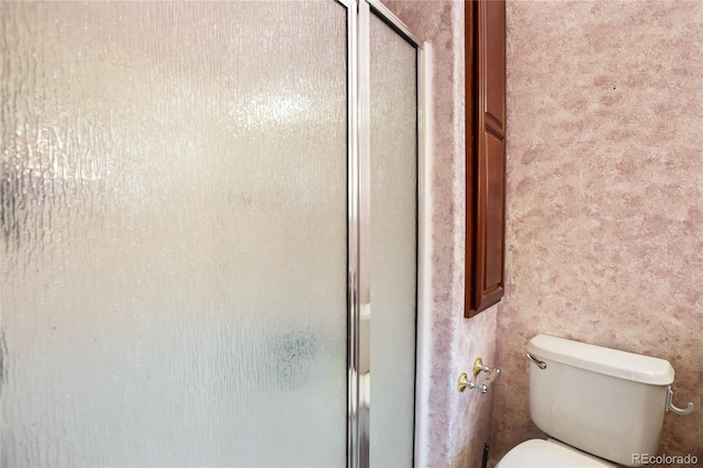 bathroom featuring toilet and an enclosed shower