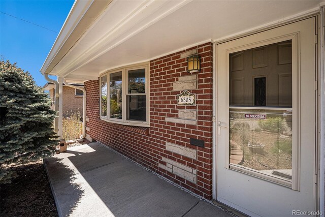 view of exterior entry featuring brick siding
