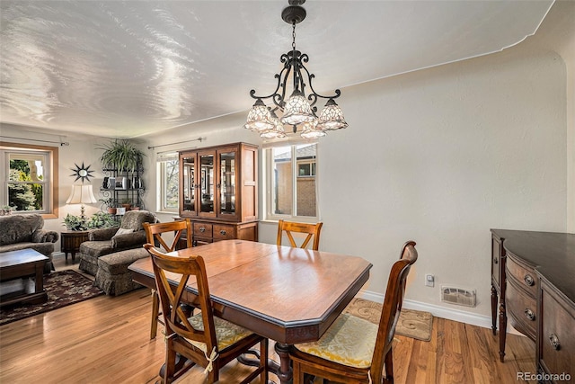 dining room featuring a chandelier, light wood-style flooring, and baseboards