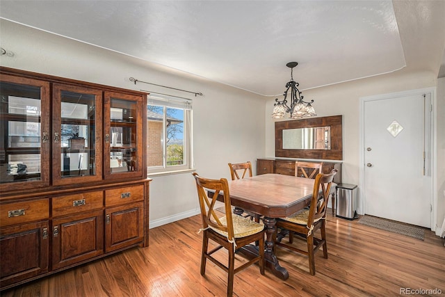 dining area with wood finished floors, baseboards, and a chandelier
