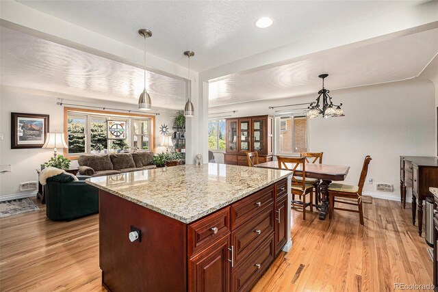 kitchen with baseboards, light wood finished floors, open floor plan, pendant lighting, and recessed lighting
