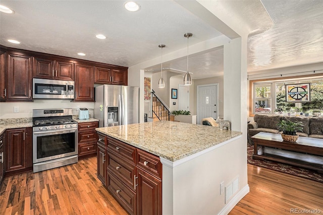 kitchen featuring stainless steel appliances, light wood-style floors, recessed lighting, open floor plan, and light stone counters