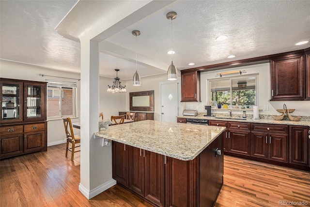 kitchen with light wood-style flooring, a sink, stainless steel dishwasher, a textured ceiling, and baseboards