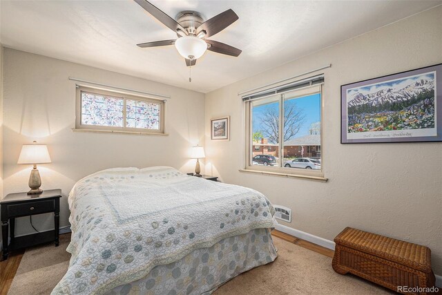 bedroom featuring wood finished floors, multiple windows, baseboards, and a ceiling fan