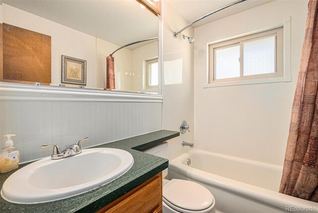 full bath with shower / tub combo, vanity, toilet, and wainscoting