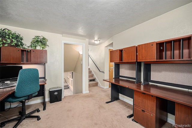 unfurnished office featuring light carpet, a textured ceiling, and baseboards