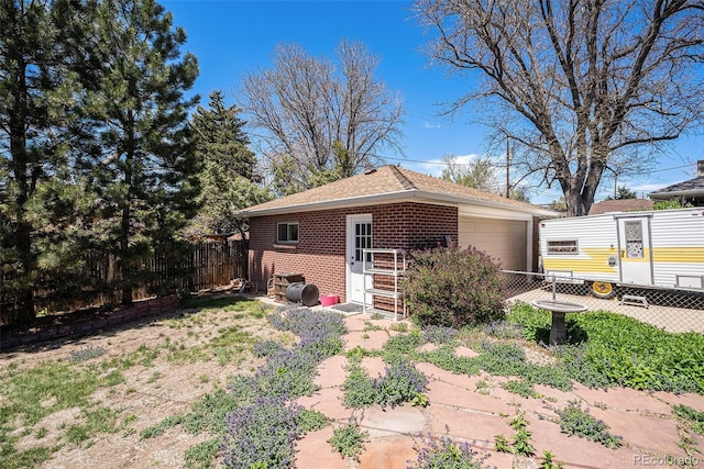rear view of property featuring fence, an outbuilding, and brick siding