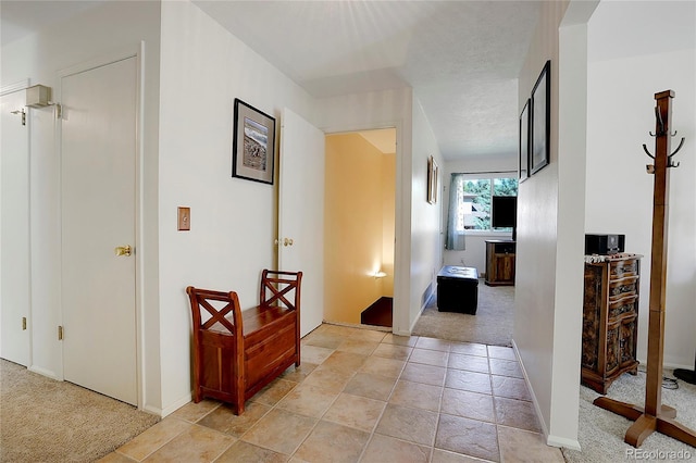 hall with light carpet and a textured ceiling