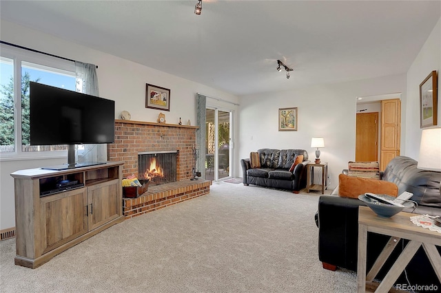 living room featuring light carpet, rail lighting, a brick fireplace, and plenty of natural light