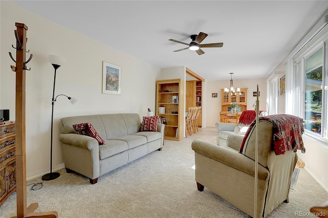 living room featuring light carpet and ceiling fan with notable chandelier