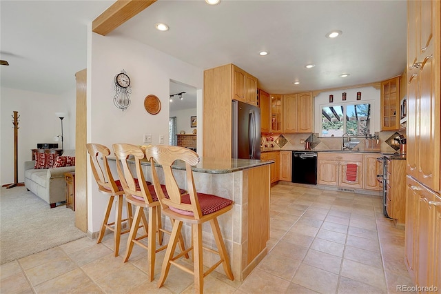 kitchen featuring light carpet, dark stone counters, a kitchen breakfast bar, sink, and appliances with stainless steel finishes