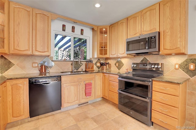 kitchen with dark stone countertops, sink, light brown cabinetry, and appliances with stainless steel finishes