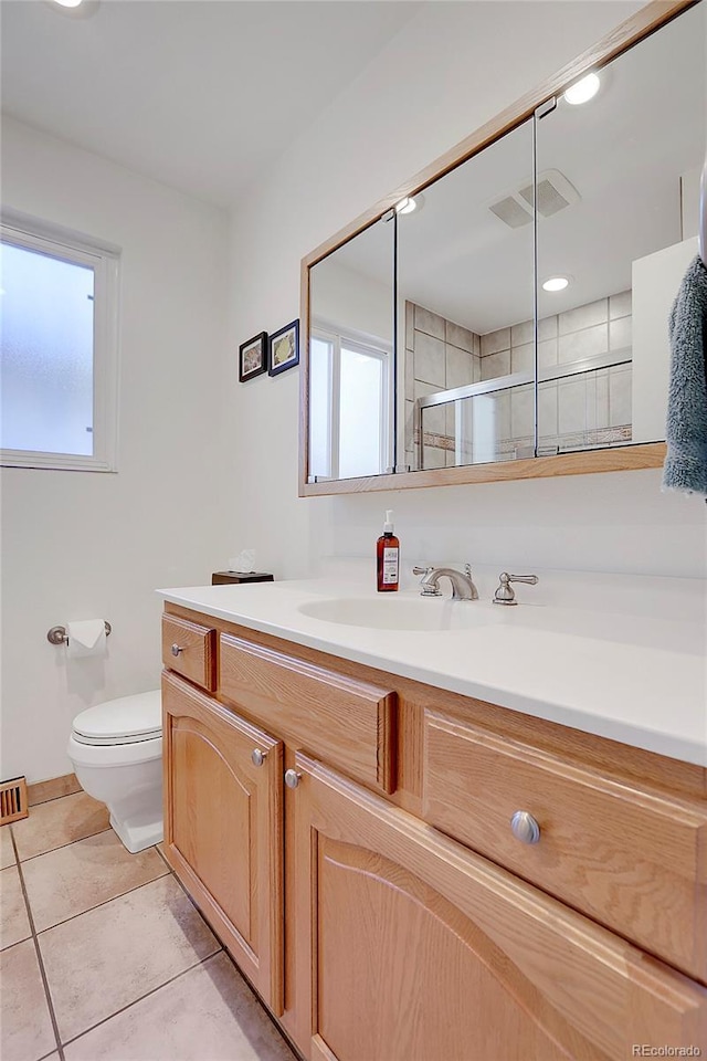 bathroom with tile patterned flooring, vanity, toilet, and a shower with door