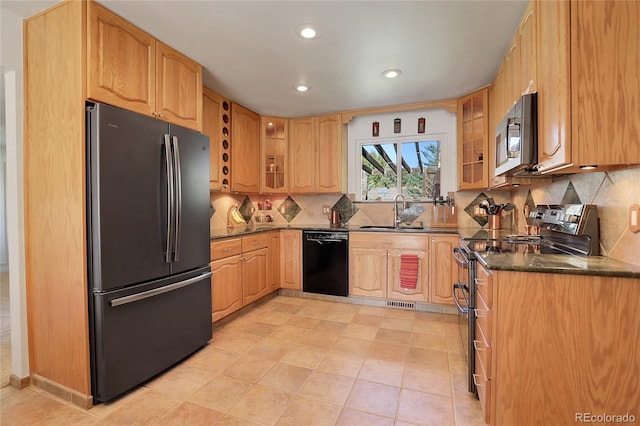 kitchen with decorative backsplash, stainless steel appliances, sink, light tile patterned floors, and dark stone countertops