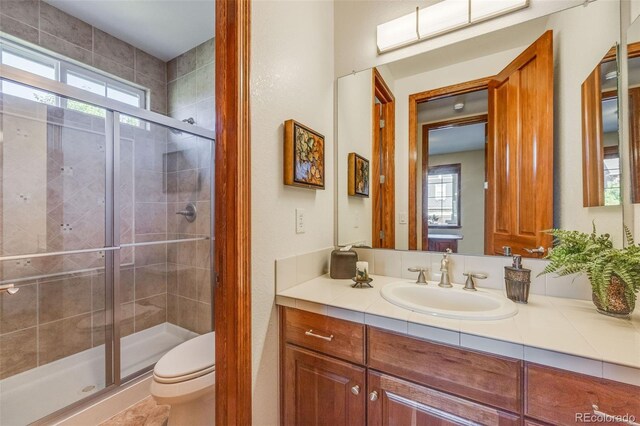 bathroom featuring walk in shower, vanity, and toilet