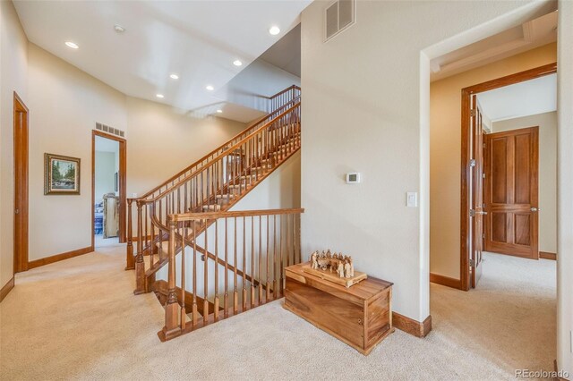 stairs with a high ceiling and carpet flooring