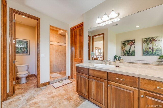 bathroom featuring a tile shower, vanity, and toilet