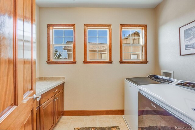 laundry room featuring separate washer and dryer, light tile patterned floors, and cabinets